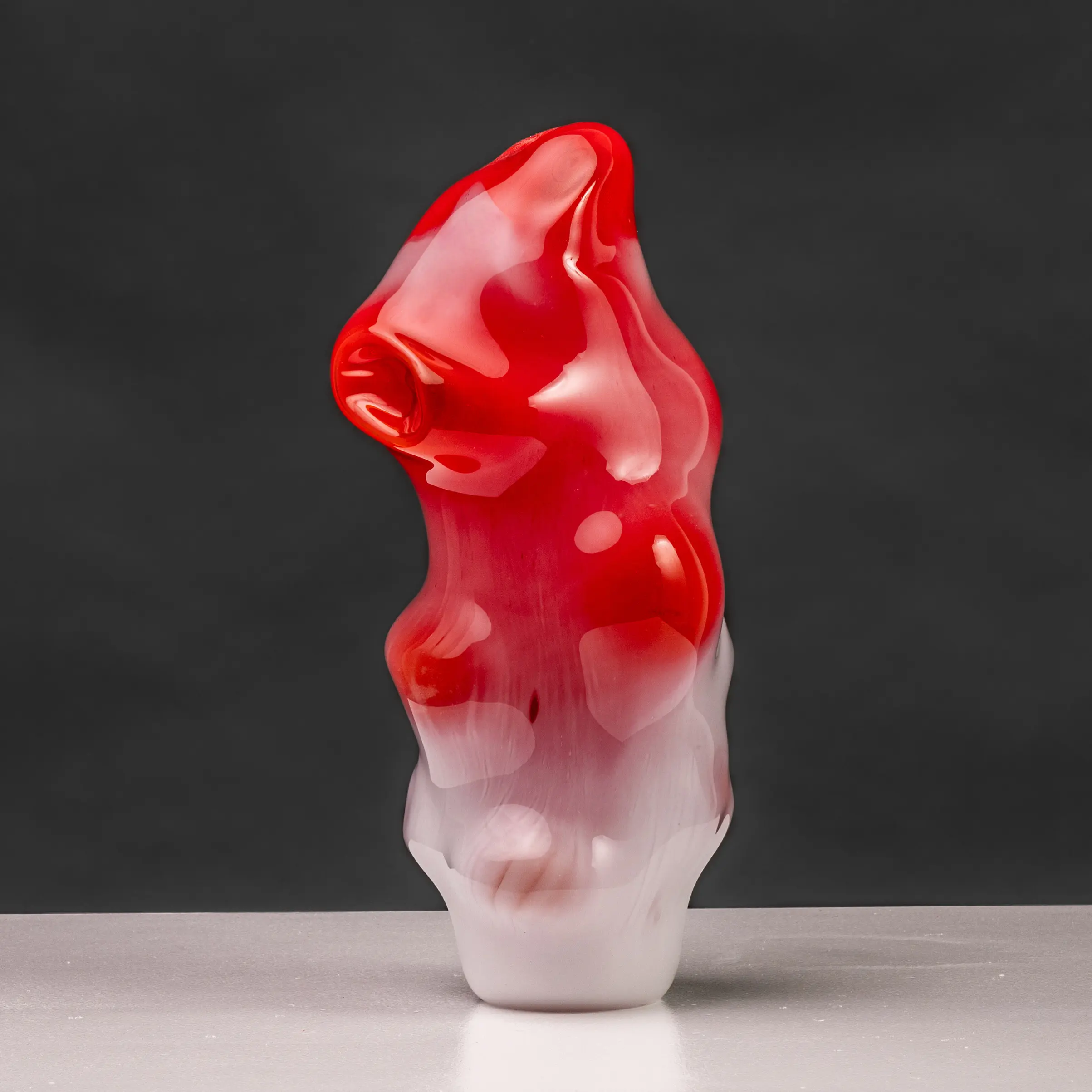 赤を基調としたガラス製の作品がある。高さがあり、横幅は短く不安定に白い床の上に立っている。赤と白の2色で構成されていて、丸い膨らみが7箇所あり、凹みが1箇所ある。色の変わり目ははっきりと分かれておらず、徐々に変化している。下の部位は白色で上に行くに従って赤色に変わる。作品の頭の部分は丸みを帯びながらも尖っていて、先端は右上を向いている。