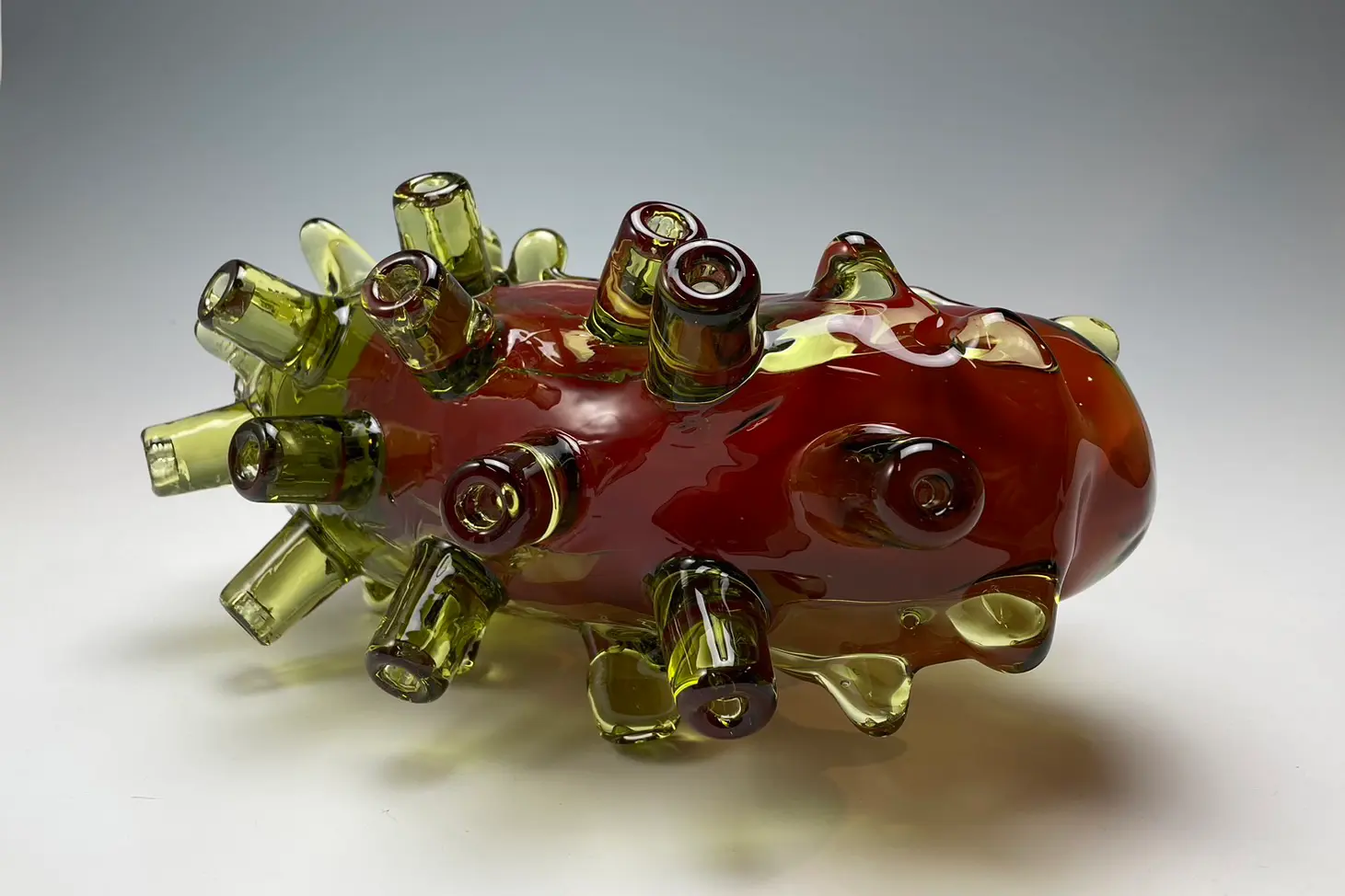 蛸の吸盤のようなパーツが表面に付いているガラス製の作品がある。赤と緑色の2色で構成されていて、内側が赤、外側が緑色である。内側の赤色は不透明でこの色から内側を見ることはできない。外側の緑色は透明で内側の赤色を見ることができる。吸盤のようなパーツは22箇所ありそれぞれ別の方向を向いている。右端の先端には吸盤のようなパーツはついておらず光沢のある滑らかな質感がある。吸盤のようなパーツは大きさがそれぞれ少し異なっている。吸盤が作品全体の重さを支えて白い床の上に立っている。